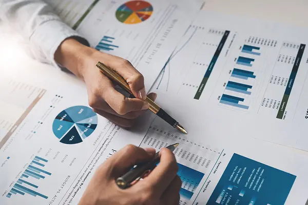 hands holding pens pointing to financial graphs